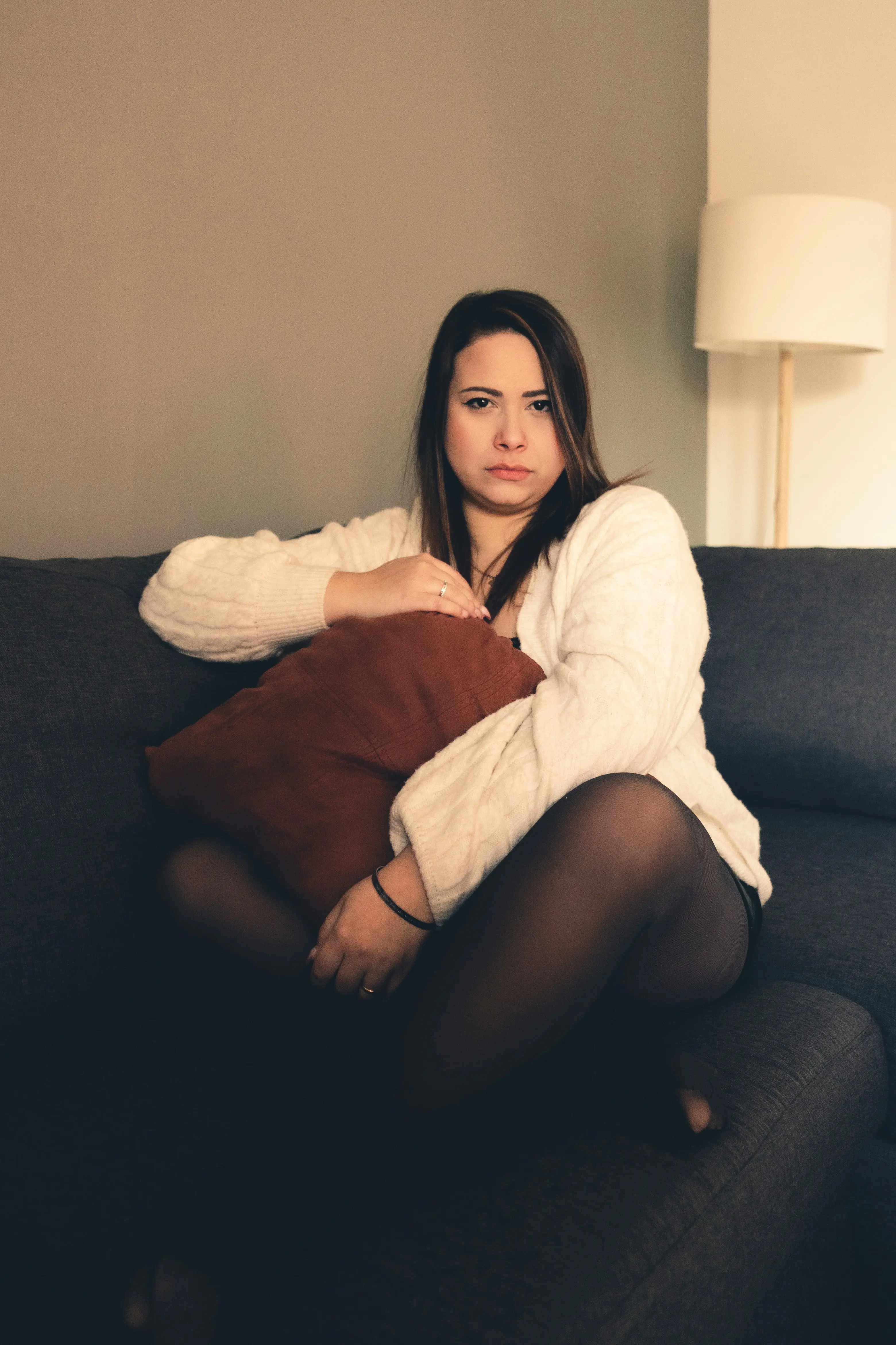 Nachdenkliche Frau sitzt auf einem Sofa und umarmt ein Kissen
